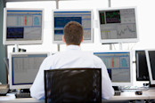 Man looking at stock charts on multiple monitors