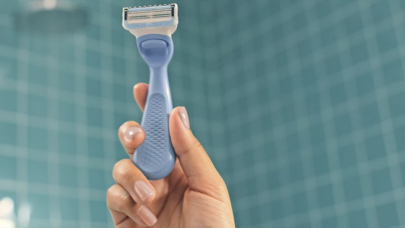 una mano di una ragazza che tiene tra le dita il nuovo rasoio per la zona intima di Gillette Venus, è evidente l’ergonomicità del manico. È di colore celeste.