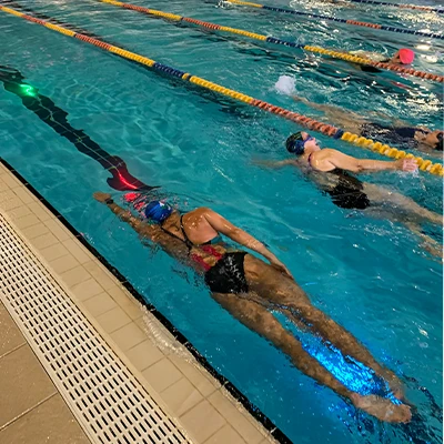 due donne nuotato in piscina, sotto di loro vi sono delle luci a led che mandano impulsi per guidarle durante l’allenamento.