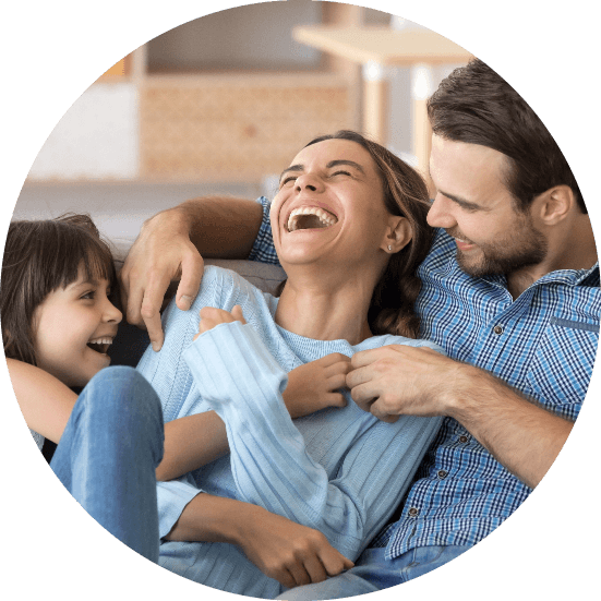 Una famiglia ride seduta sul divano di casa.