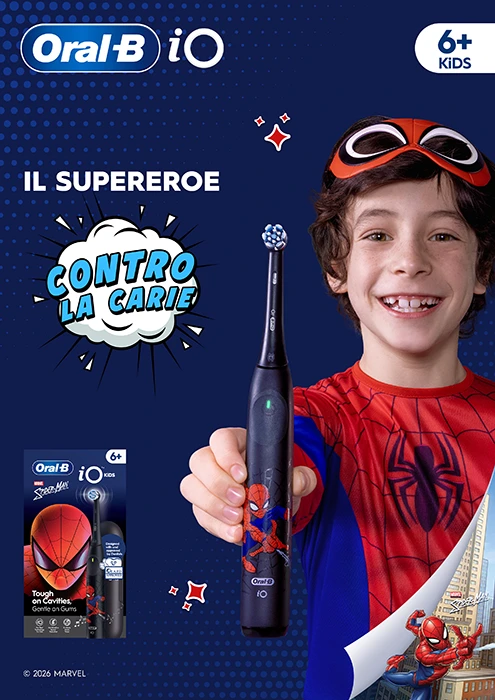 oralb io kids il super eroe contro le carie. Un bambino con una macheda di spiderman poggiata sui capelli indossa una maglietta di spiderman e sorride mostrando il suo oral b io kids di spiderman.