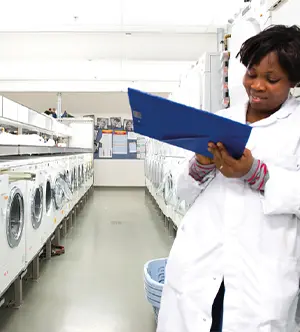 una ricercartice di dash indossa un camice bianco e si trova all'interno di un laboratorio con tante lavatrici