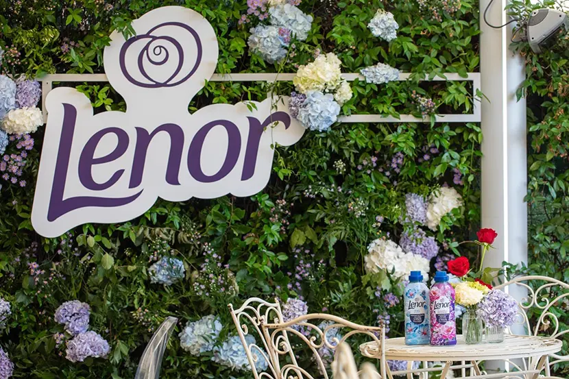 Due ammorbidenti Lenor su un tavolino, sullo sfondo alcuni fiori e il marchio Lenor.