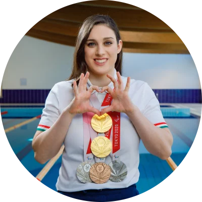 Carlotta Gilli, campionessa di nuoto che parteciperà ai Giochi Olimpici e Paralimpici di Parigi 2024, a bordo piscina con alcune medagli.