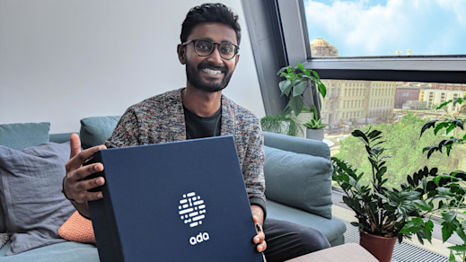 Gobie holding a navy blue employee box featuring Ada's logo. Gobie holding a navy blue employee box featuring Ada's logo.