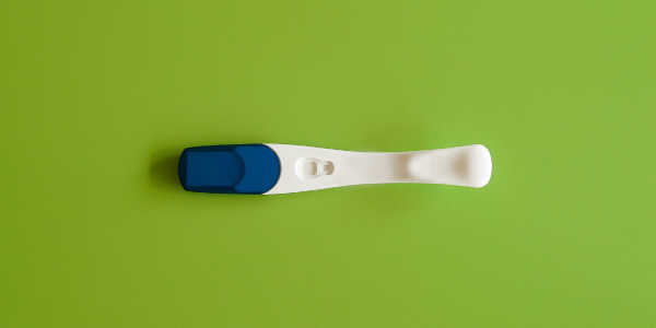 在明亮的绿色表面上的怀孕测试的照片