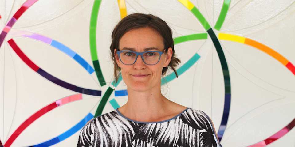 portrait of ida tin in front of a colourful flower petal wall in the clue headquarter in berlin
