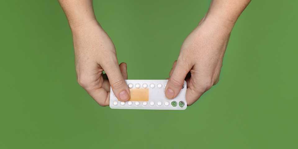 Deux mains tenant un paquet de pilules contraceptives.