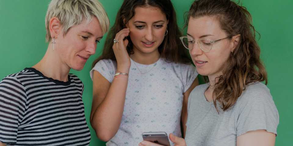 Three women looking at a phone