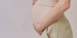 一个怀孕的人把手放在肚子上的图像