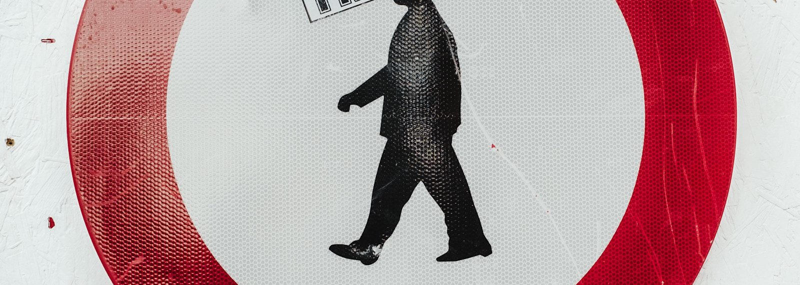 Image of a street sign, defaced with the word trust on a human head