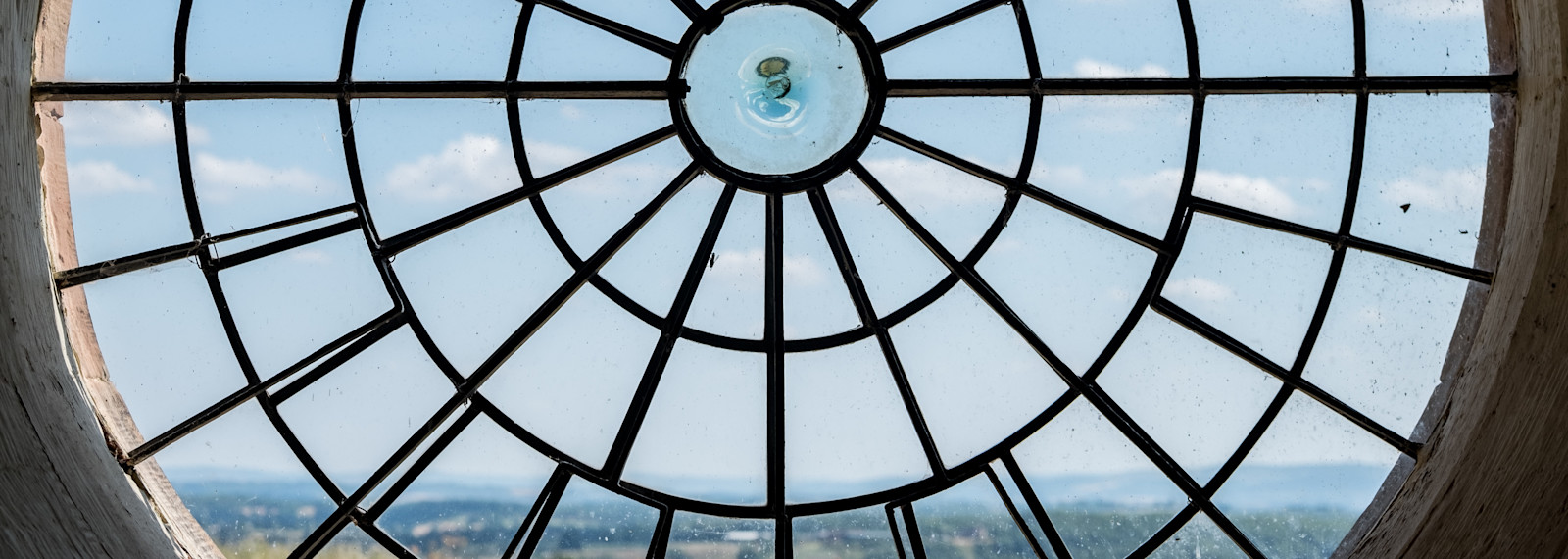 Image looking through out of a large circular window to a rural scene