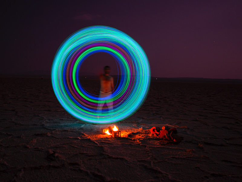 image of an illuminated circle above a camp fire and in front of a figure