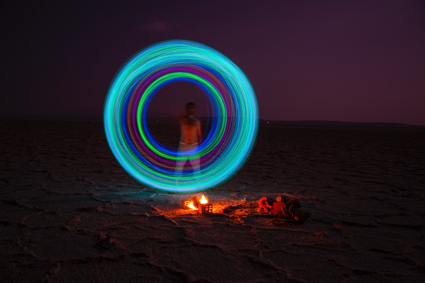 image of an illuminated circle above a camp fire and in front of a figure
