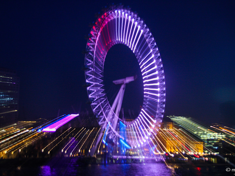 Illuminated Ferris wheel against the night sky in a cityscape