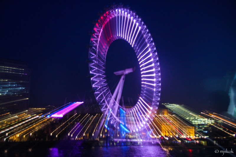 Illuminated Ferris wheel against the night sky in a cityscape