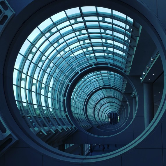 Looking down a circular glass tunnel towards a corporate looking building