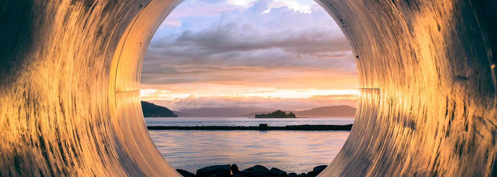 Image looking out at a waterscape through a circular tunnel
