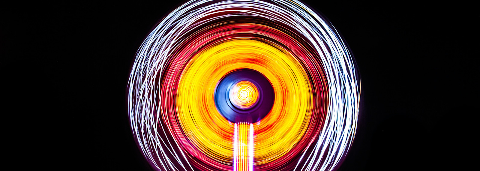Image of circular light image emitted by a Ferris wheel in the night sky