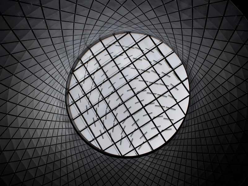 Looking up at a patterned glass ceiling through a circular tunnel