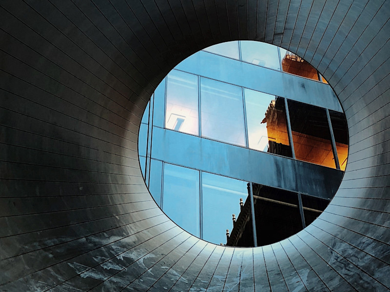Image of looking through a circular tunnel towards an office building