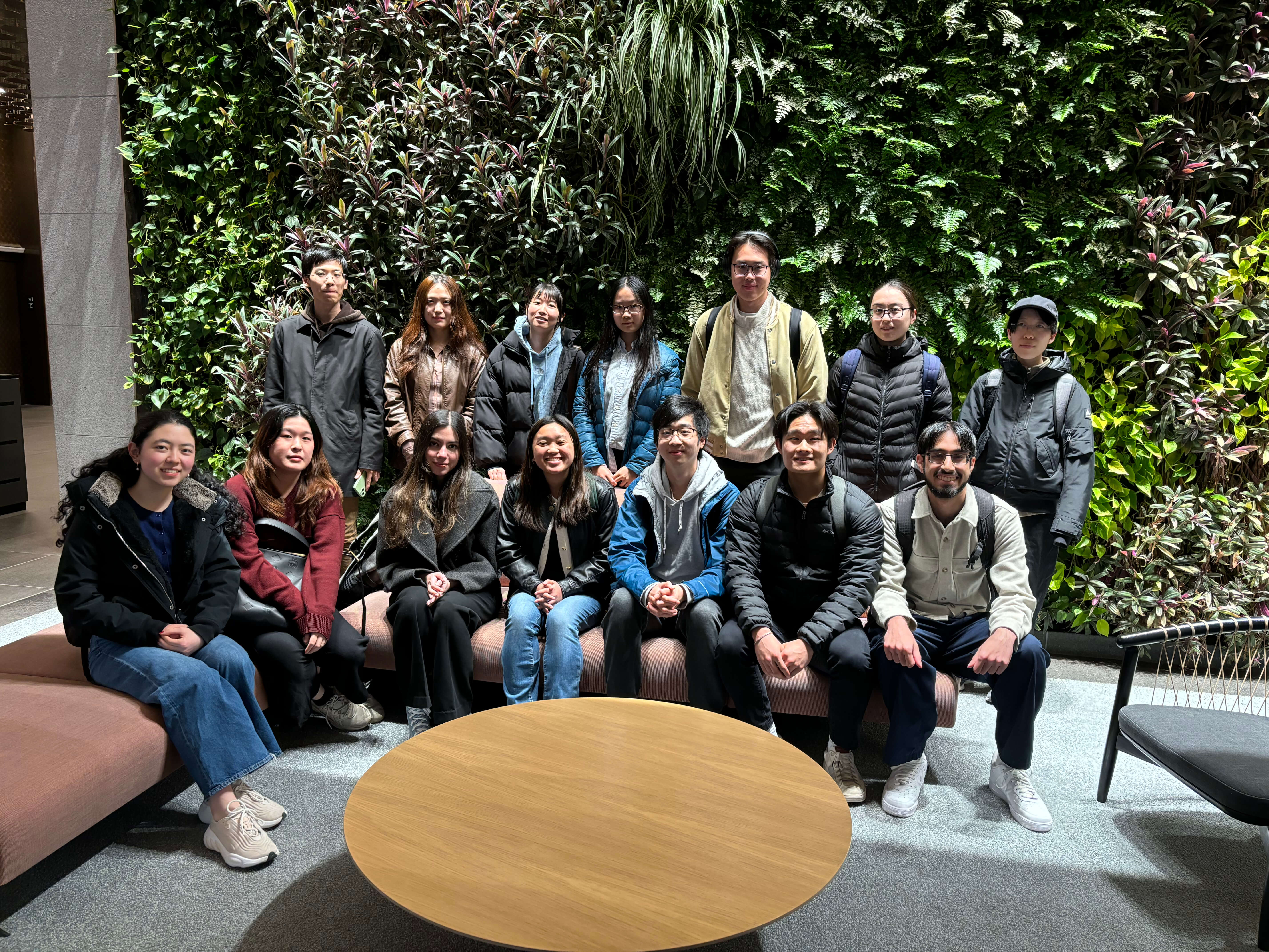 Group of Rippling interns posing in front of a wall of plants.