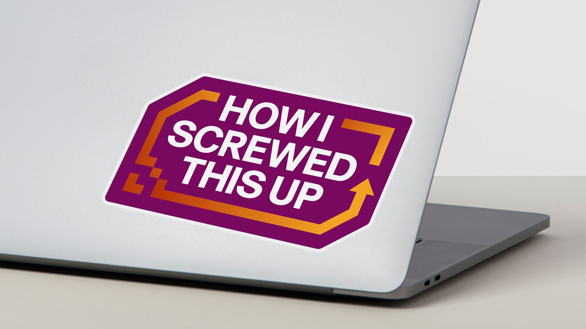 Photograph of a laptop with a sticker on the cover that says How I Screwed This Up
