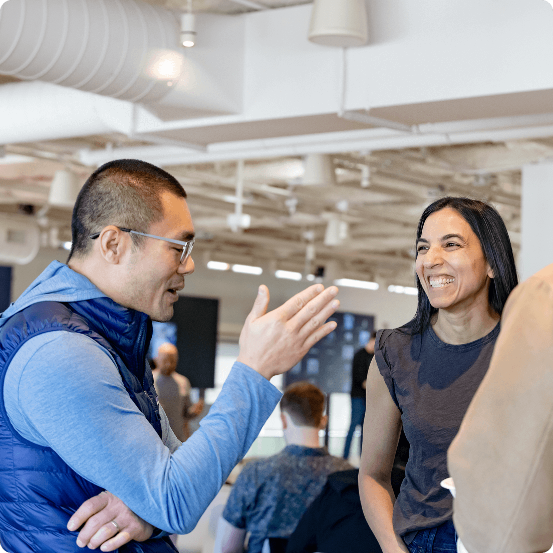 A photograph of two event attendees smiling and talking in an industrial style office
