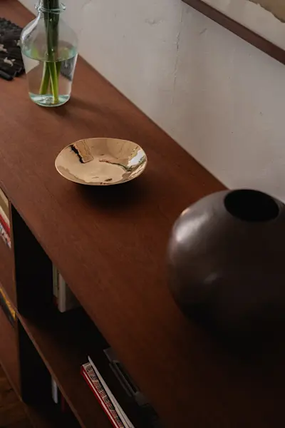 A Nancy Pearce Small Bronze Bowl and Logan Wannamaker Ceramic Vase resting on a bookshelf designed by Josie.