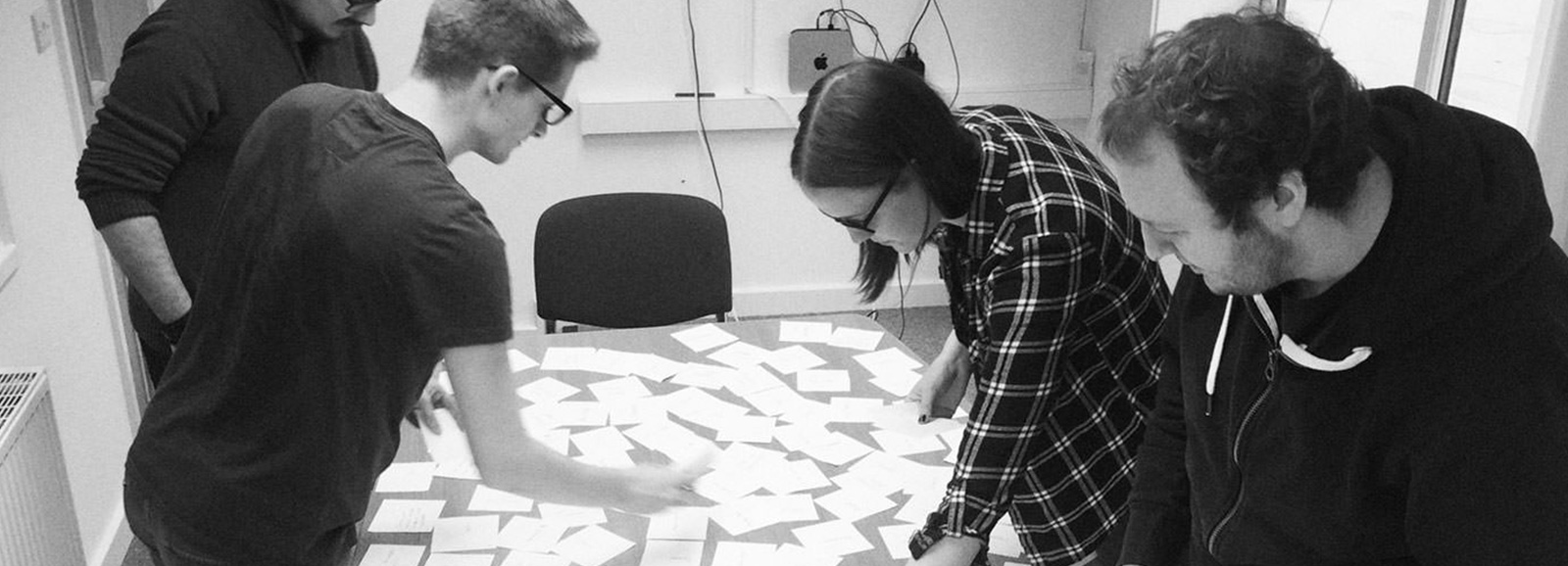 People stood around a table that is filled with notes during a UX design sprint