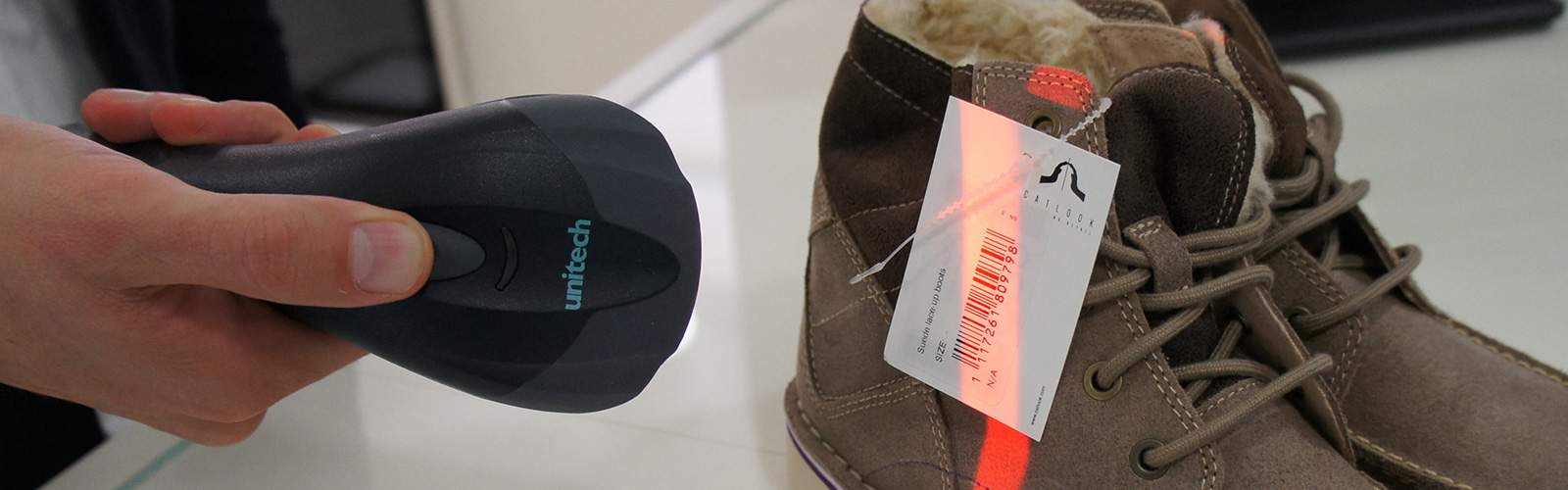 Someone scanning a barcode on the label of some brown boots with a barcode scanner