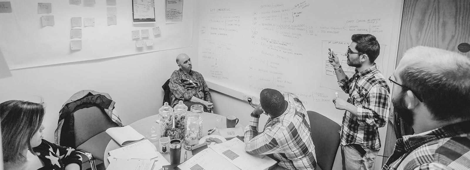 Eden Digital Agency employees and clients sat around a table while one person is presenting their ideas in the Eden Sprint Week, which is a UX design sprint workshop.