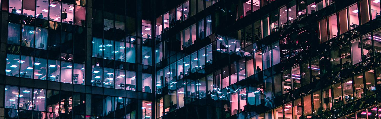 Office block at night with varied almost neon coloured lights coming from the windows