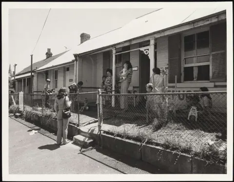 Mother&#39;s and their children outside the Elsie Women&#39;s Refuge, mid-1970&#39;s. “We got a huge amount of media coverage. John Laws was on commercial radio in Sydney in those days and had me on his program, and we talked for a long time. He kept repeating the Eslie’s phone number, and it was amazing the number of women who came to us who had heard that broadcast and had written down the phone number as a result. He kept repeating the phone number even after I left the studio, that kind of support got it out to the right audience.&quot; Prof Summers talks of the word spreading about Elsie Refuge in the first few days. Image: courtesy of National Library of Australia, PIC Box #PIC/20681/2  