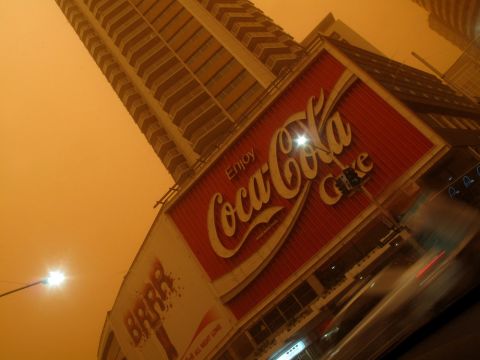Coca Cola sign and orange sky in Kings Cross during dust storm, 2009 (City of Sydney Archives, photographer Gary Deirmendjian, A-00063644)