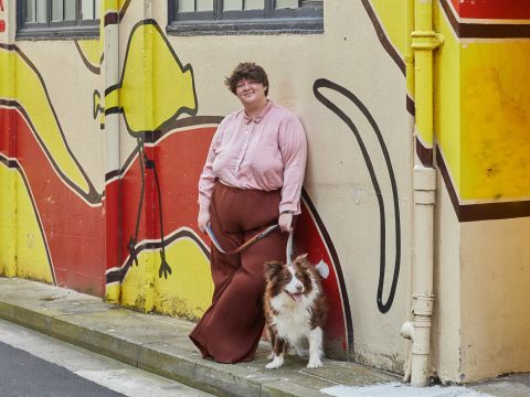 Amy Sole and their pooch in front of the Gadigal Mural in Darlinghurst. The mural is the work of 3 Aboriginal artists: Dennis Golding, Lucy Simpson and Jason Wing. Their work references both the topographical patterning and material culture of Gadigal country. Photo: Rob Hookey / City of Sydney
