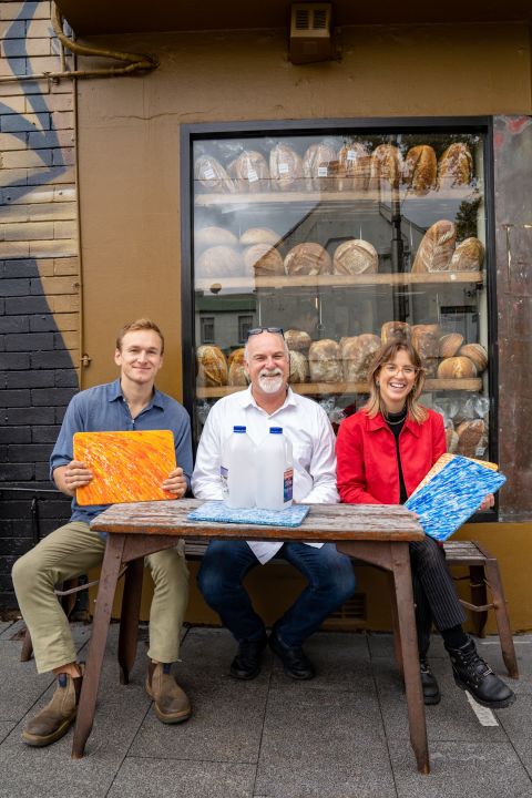 Will Thompson, director of Defy Design, David McGuinness co-owner Bourke Street Bakery, and Marne Dingwall, designer at Defy Design, show their recycled milk bottle chopping board. Photo: Abril Felman / City of Sydney