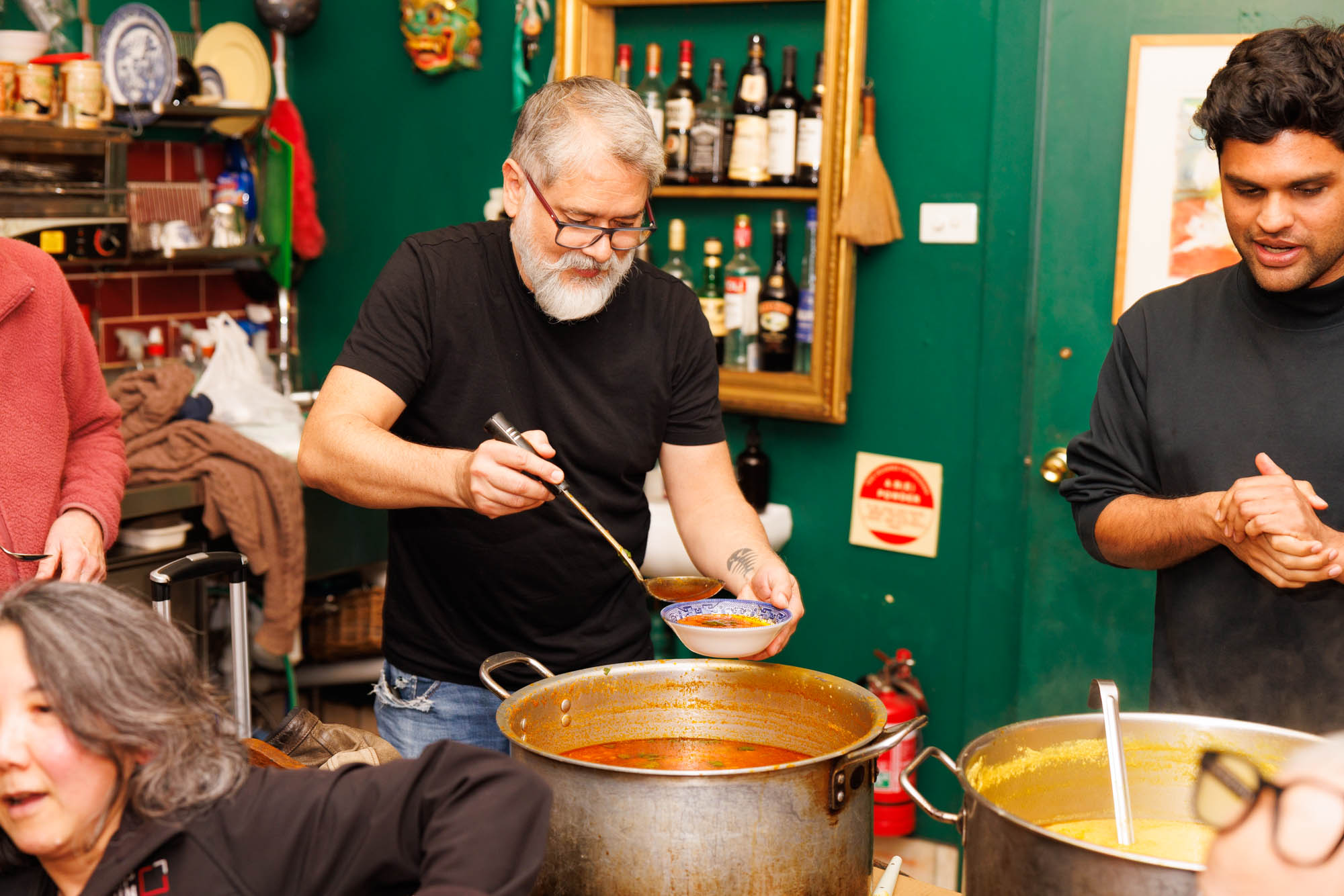 Volunteer Karim ladles soup into a bowl. Image credit: Phoebe Pratt / City of Sydney