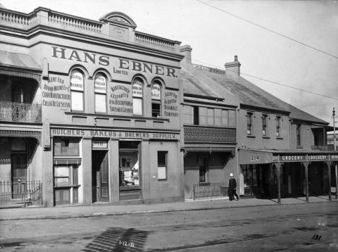 Shows policeman in topee hat walking along west side of Harris street near grocery store (214), terrace house (212), Hans Ebner Ltd Butchers, Bakers and Brewers Supplier. Photograph 208-214 Harris Street Pyrmont, 1911 City Archives A-00038940