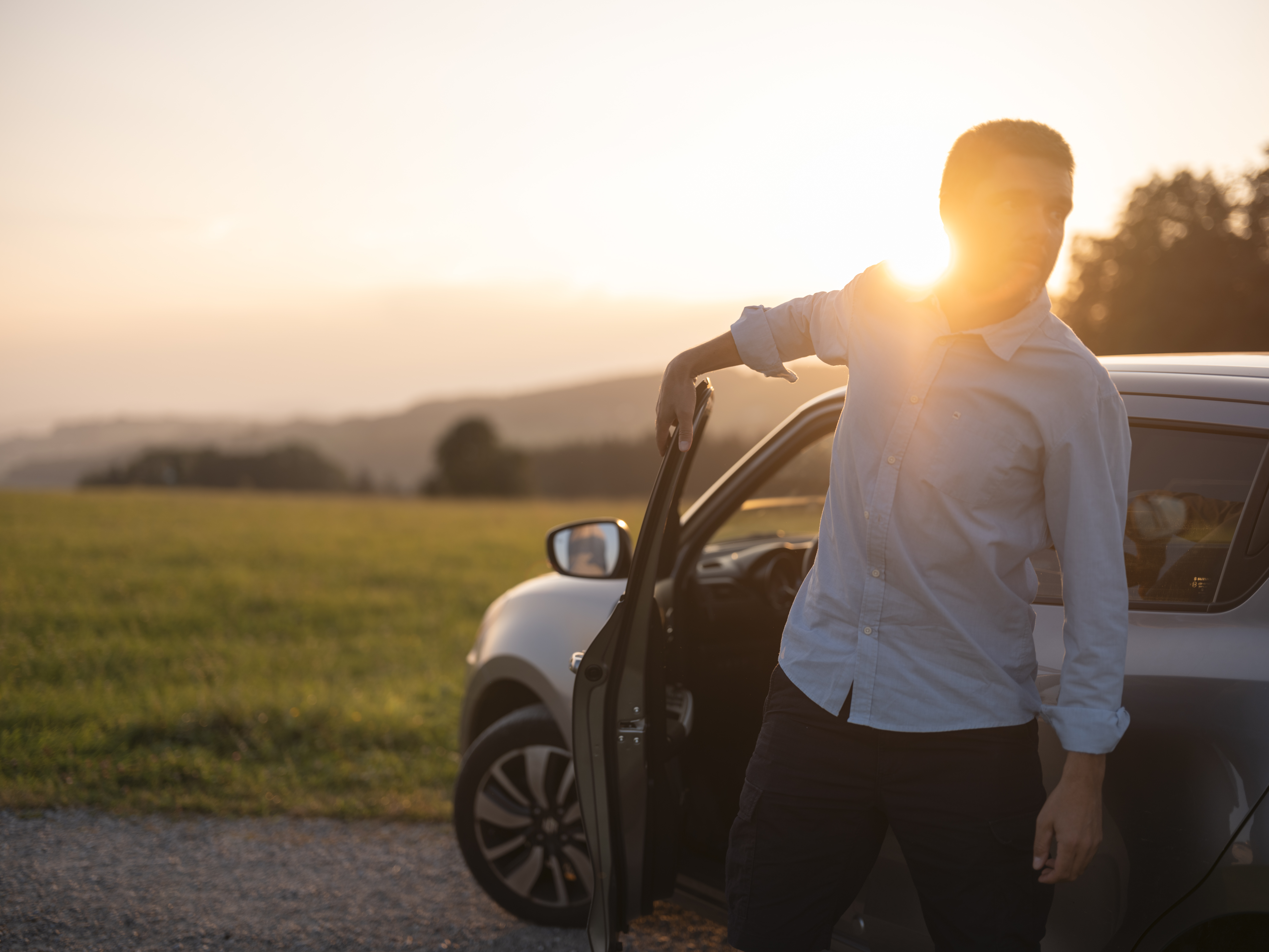 Bild Mobilität - Mann steigt aus Auto aus bei Sonnenaufgang