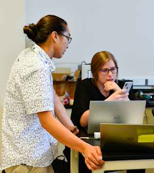 Two CU students, one male and one female, discuss their test using a mobile device.