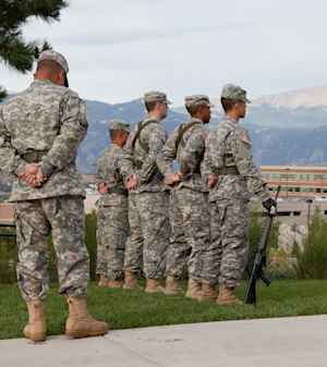 Four US Army soldiers and their commander stand at attention to the US flag on the University of Colorado Colorado Springs campus.