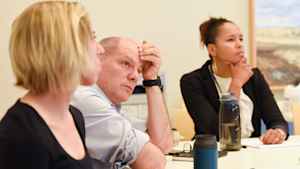 Dr. Fernando Holguin sits at a conference table, his hand to forehead, listening intently about the preliminary study results.