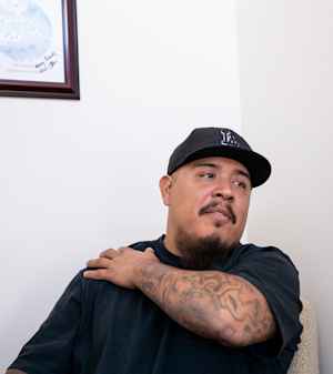 Mike turns to his left with his right crossing his upper body as he talks during therapy.
