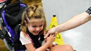 A young girl laughs after she kisses the hand of her occupational therapist.