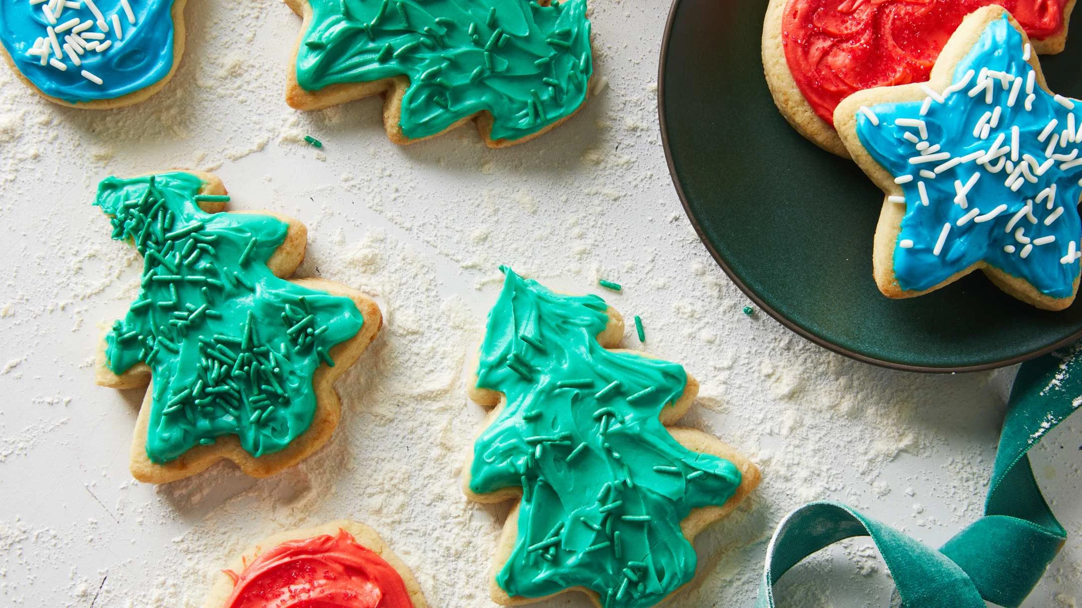 Holiday sugar cookies with green tree shapes, blue and red star shapes, decorated with colorful frosting and sprinkles.