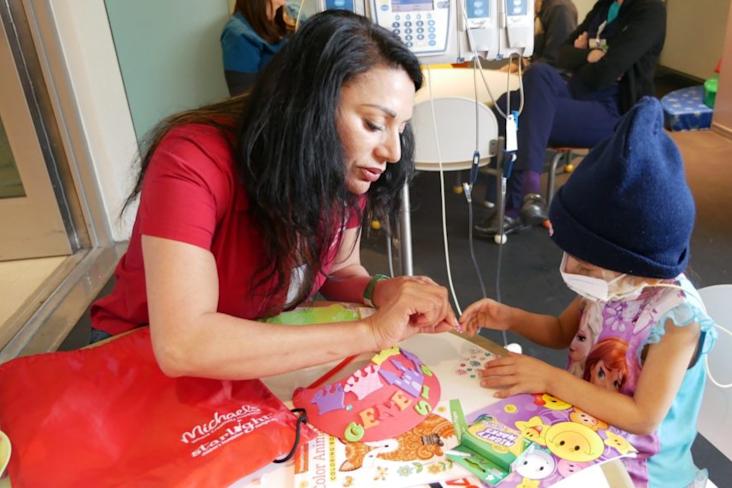 MICHAELS ASSOCIATE HELPING GENESIS DECORATE HER VISOR.
