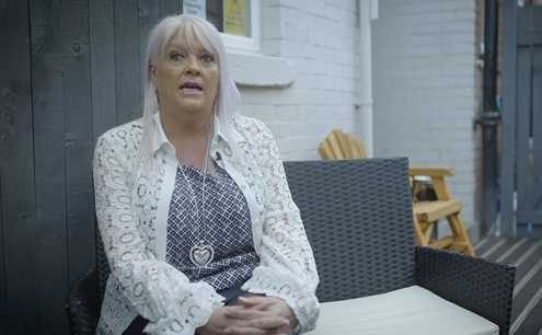 Woman sitting in pub beer garden, giving interview