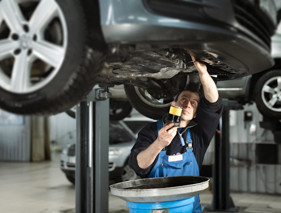 Garagiste qui inspecte une voiture par le dessous