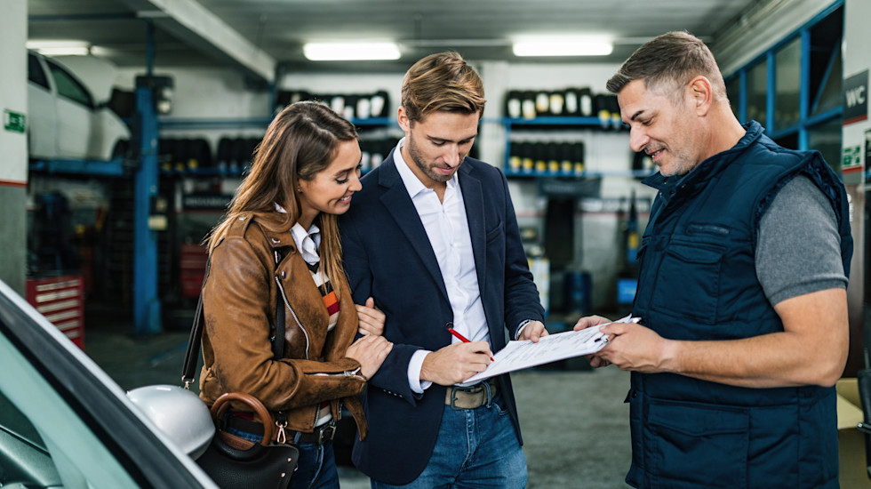 Couple heureux qui signe le devis d'un garagiste
